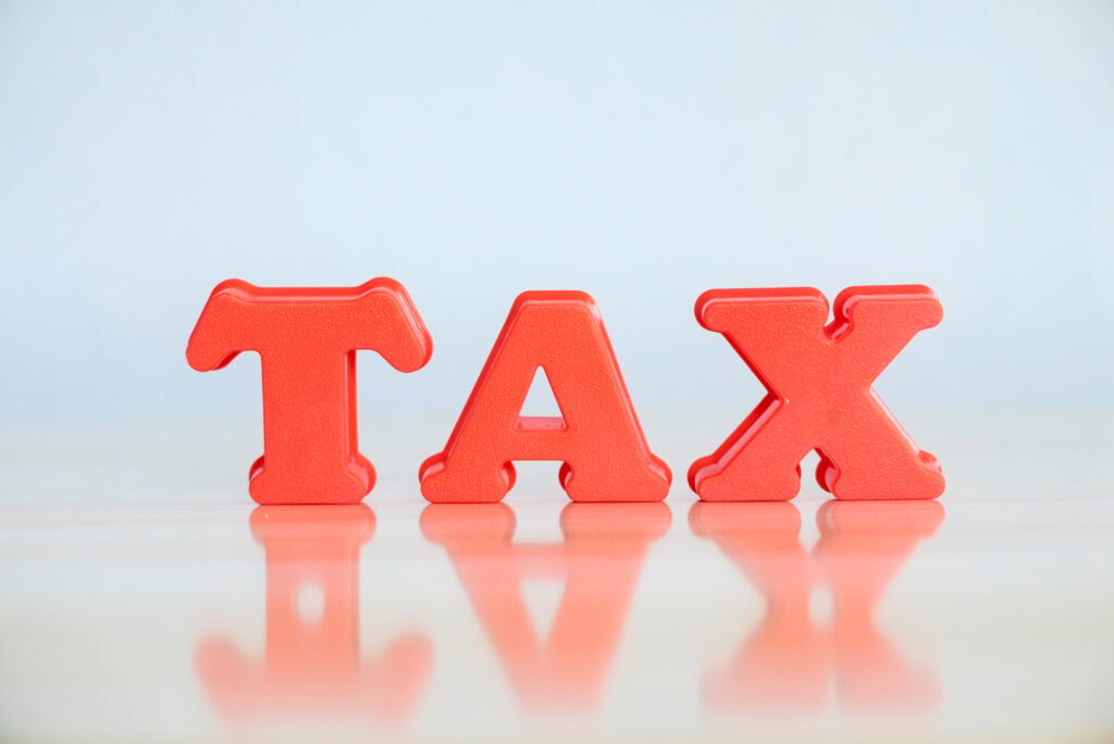Tax concept. Red alphabet of word tax on wooden background.